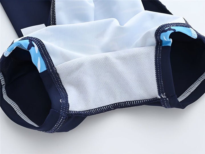 Combinaison de bain pour enfant à manches courtes, bleu clair avec motif de baleines et de queues de baleines, manches et côtés bleu marine. Idéal pour la piscine ou la plage.