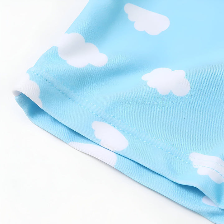 Combinaison flottante pour enfant, motif avions sur fond bleu ciel avec nuages blancs. Manches à flotteurs intégrés. Aide à l'apprentissage de la natation, sécurité aquatique, design ludique pour les enfants.