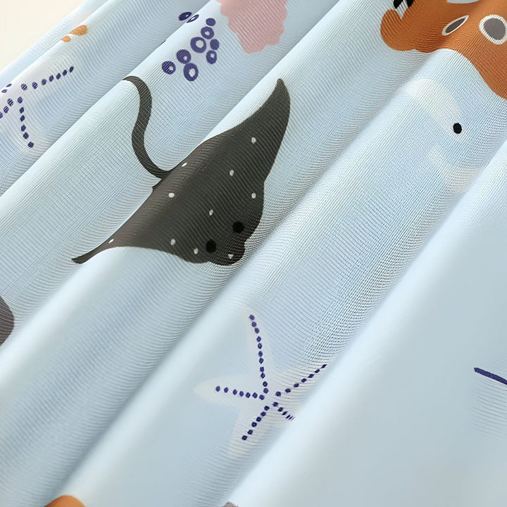 Bonnet de bain bleu clair avec motifs marins : crabes, étoiles de mer, raie manta, et sous-marin. Accessoire pour la natation des enfants.