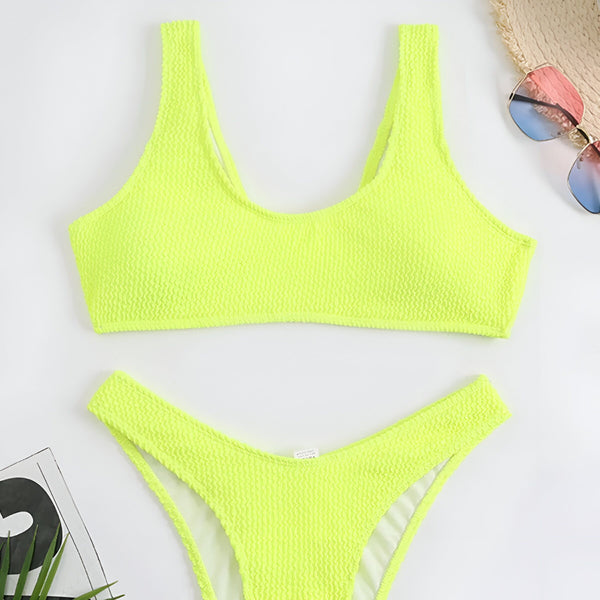 Femme en bikini noir texturé sur la plage, bronzée, mains avec bagues, ventre plat. Mode été, maillot de bain, vacances. Peau éclatante, soleil. Détails du tissu, accessoires.