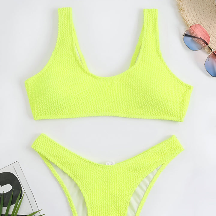 Femme en bikini noir texturé sur la plage, bronzée, mains avec bagues, ventre plat. Mode été, maillot de bain, vacances. Peau éclatante, soleil. Détails du tissu, accessoires.