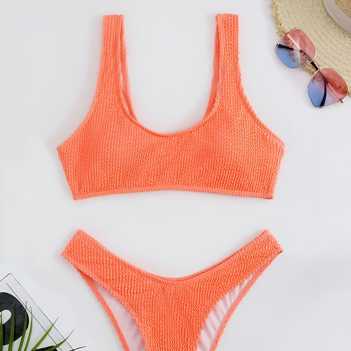 Ensemble de bikini rose vif texturé avec un chapeau de paille et des lunettes de soleil aux verres dégradés. Idéal pour la plage ou la piscine, mode estivale, accessoires de vacances.