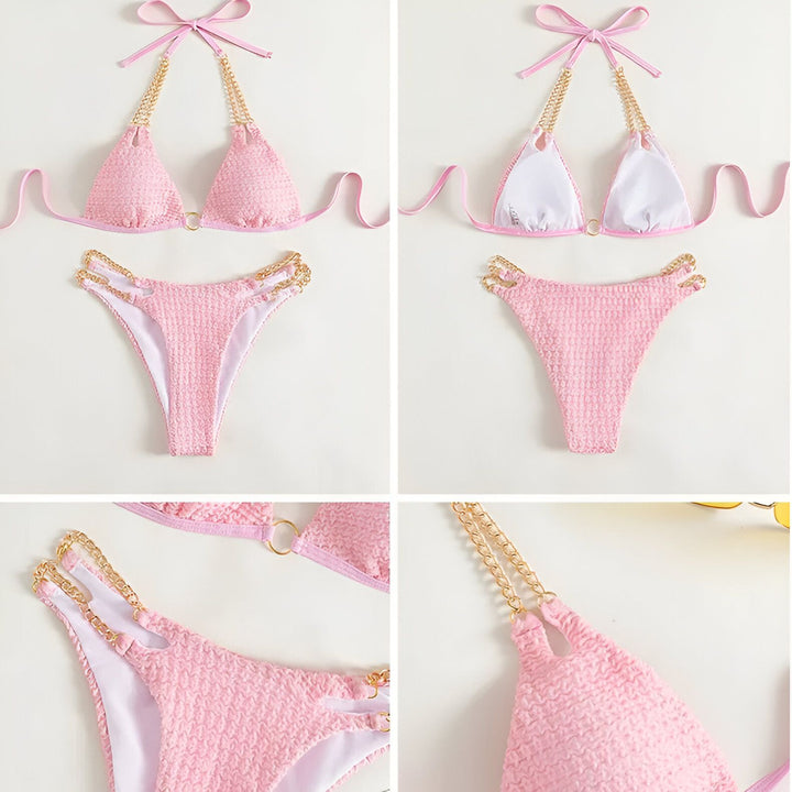 Femme en bikini bleu texturé, orné de chaînes dorées, tenant un verre de vin. Manucure bleue assortie. Mode estivale, élégance balnéaire.