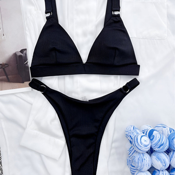 Image d'un ensemble de bikini rouge vif sur un fond de chemise blanche et une jupe noire en similicuir. Des boules décoratives bleues et blanches ajoutent une touche colorée. Mode estivale et ambiance plage décontractée.