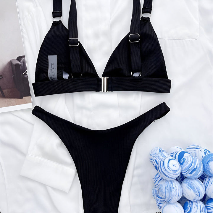 Vue rapprochée d'un bikini rouge côtelé avec un haut triangle et une culotte assortie, posé sur une jupe en cuir noir et une chemise blanche.