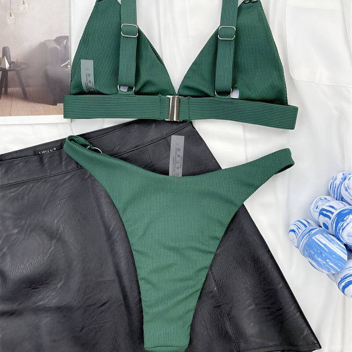 Image d'une femme portant un bikini corail avec des anneaux dorés et une veste blanche. Mode estivale, maillot de bain tendance.