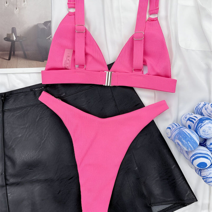 Image d'une femme portant un bikini vert avec des détails dorés, et un blazer blanc. Le bikini est de style triangle et semble côtelé. Le blazer blanc est décontracté sur les épaules.