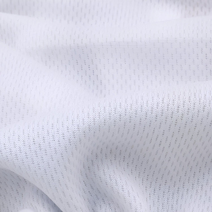 Texture de tissu blanc ajouré en gros plan, motif de trous fins. Détails de textile léger et respirant, idéal pour vêtements de sport ou doublure. Vue rapprochée de maille blanche froissée.