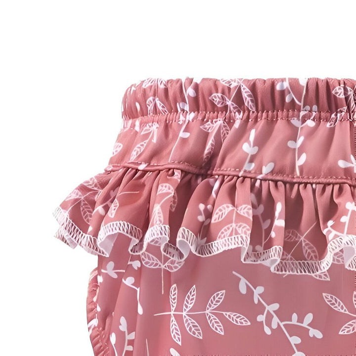 Culotte de bain pour bébé avec motif floral blanc sur fond jaune. Volant décoratif autour de la taille élastique. Idéal pour la plage ou la piscine.