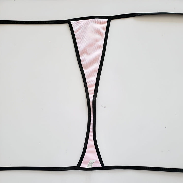 Femme blonde en bikini rouge et noir sur une plage, mer en arrière-plan. Elle pose avec une main dans ses cheveux, regardant la caméra. Style de vie, vacances à la plage, mode estivale.