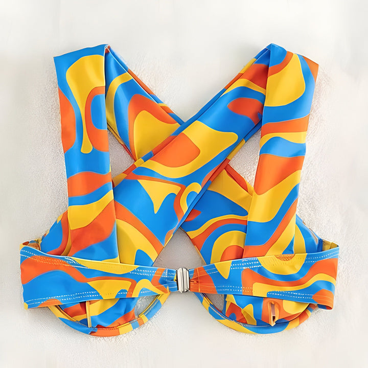 Femme portant un bikini taille haute avec un motif tourbillon bleu, orange et jaune. Vêtement de plage tendance et coloré.