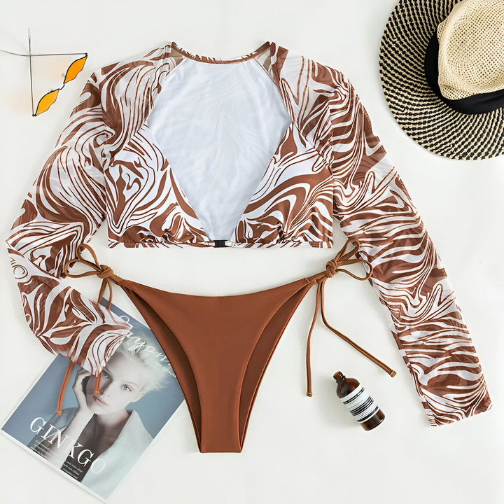 Gros plan d'une femme portant un bikini violet et blanc à motifs ondulés avec des manches longues assorties.