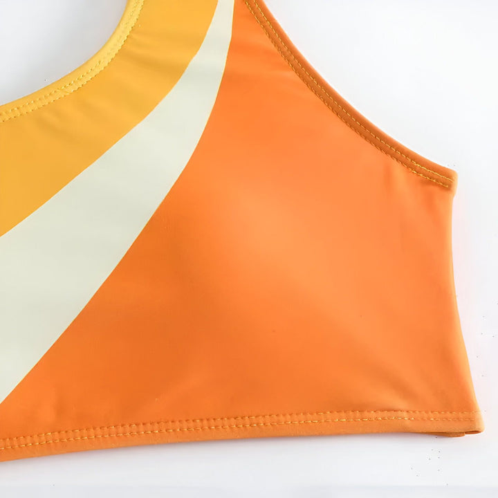 Ensemble de bikini une pièce asymétrique orange, jaune et blanc. Haut à une épaule et culotte taille haute, style plage tendance. Vêtement de bain moderne et coloré pour l'été.