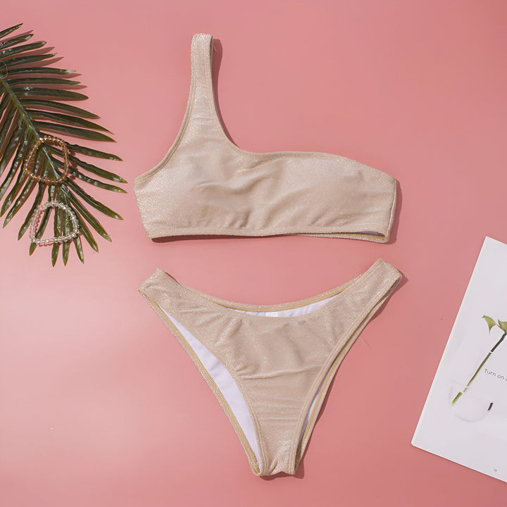 Ensemble de bikini une épaule argenté scintillant. Maillot de bain deux pièces tendance pour la plage et la piscine. Haut asymétrique et culotte échancrée pour un look estival élégant.