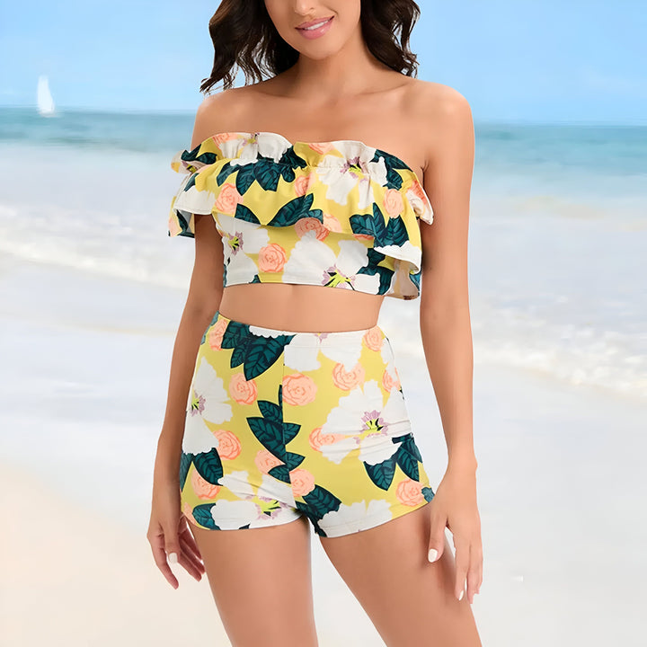 Femme souriante posant en ensemble deux pièces à motifs floraux colorés, composé d'un haut à une épaule et d'un short. Mode estivale.