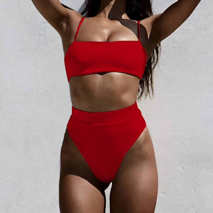 Image d'un maillot de bain deux pièces rose, haut bandeau à fines bretelles et bas taille haute, avec un chapeau de paille orné de fleurs colorées. Idéal pour la plage ou la piscine en été.