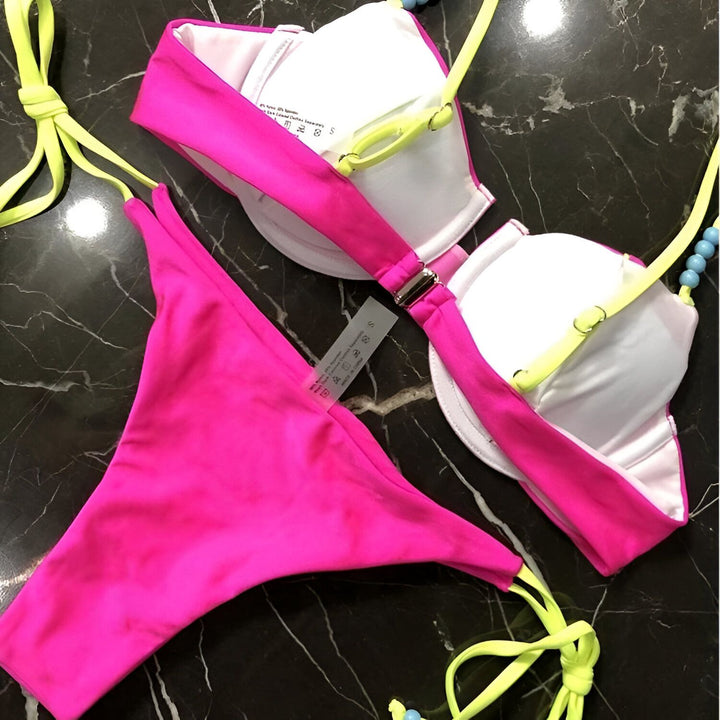 Ensemble de bikini turquoise et violet sur bois. Haut de bikini bandeau avec armatures, culotte taille basse à nouer sur les côtés. Mode été, vêtements de plage.