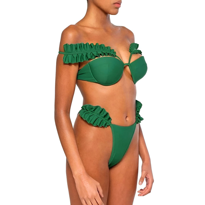 Femme portant un bikini vert avec des volants, posant sur un fond blanc. Maillot de bain deux pièces avec un haut à armatures et une culotte taille haute. Mode été, vêtements de plage.
