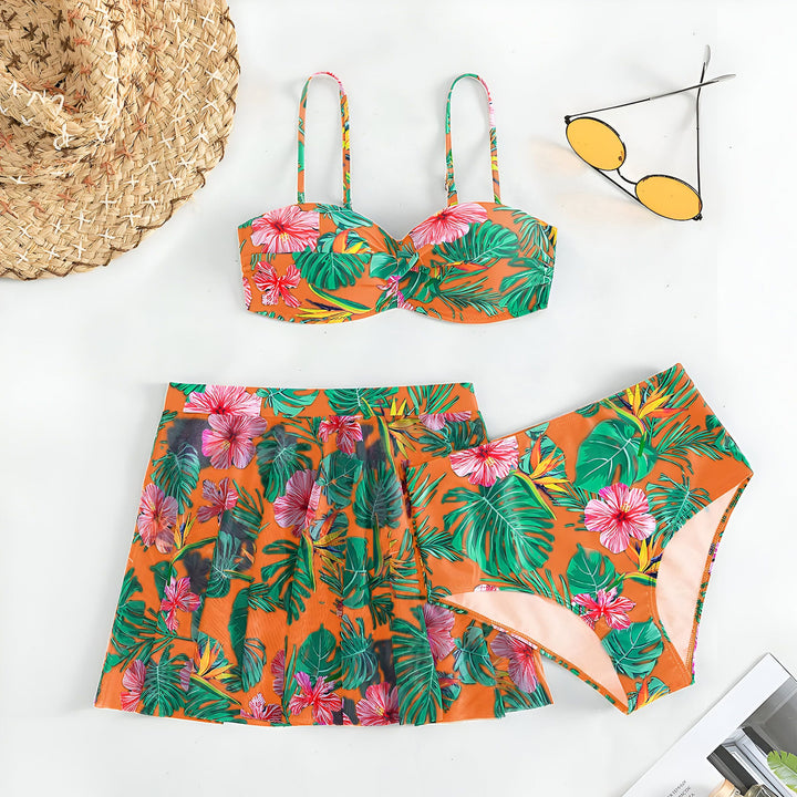 Femme vue de dos portant un bikini et une jupe de bain assortis avec un motif floral tropical bleu et rose.