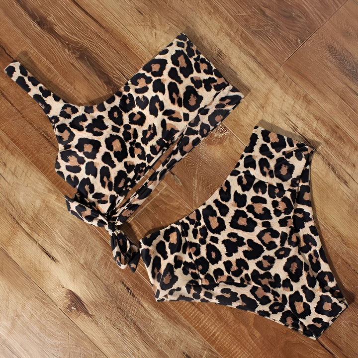 Une femme portant un maillot de bain léopard deux pièces, avec un haut asymétrique à une seule bretelle et une culotte taille haute.