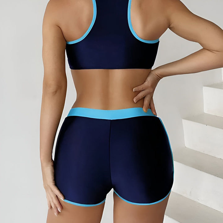 Vue arrière d'une femme portant un ensemble de sport bleu marine et turquoise composé d'un haut de sport et d'un short.