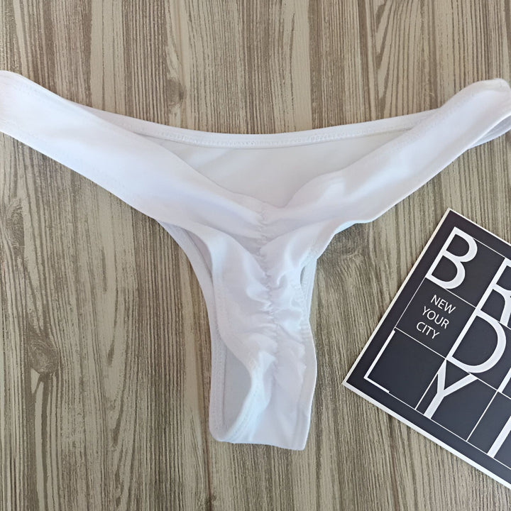 Culotte de bikini orange vif avec cordon, posée sur un fond en bois rustique près d'une carte postale de New York. Idéal pour la plage ou la piscine.