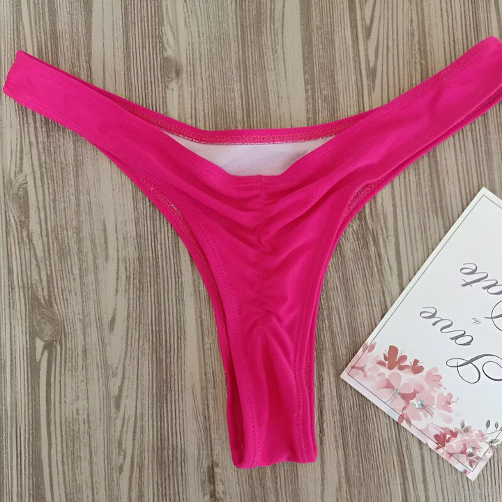 Culotte de bikini noire avec ourson en peluche violet sur fond de bois.