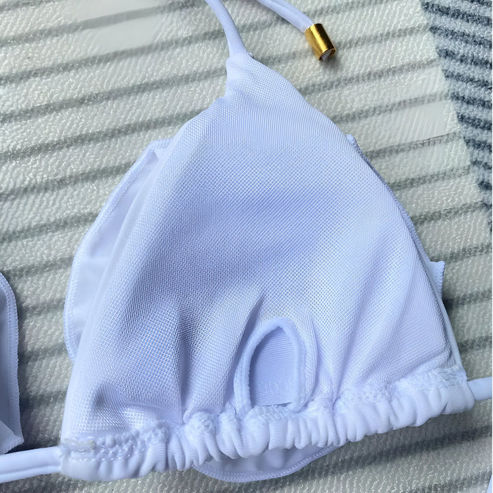 Femme en bikini rose avec des fleurs sur le haut, posant devant un rocher. Maillot de bain d'été tendance et élégant. Idée de look pour la plage ou la piscine. Mode balnéaire, vacances ensoleillées.