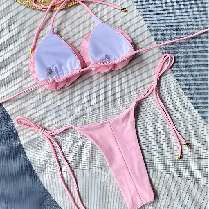 Femme portant un bikini blanc avec des fleurs, posant devant une formation rocheuse. Maillot de bain tendance pour l'été, idéal pour la plage. Mode estivale, style élégant et féminin.