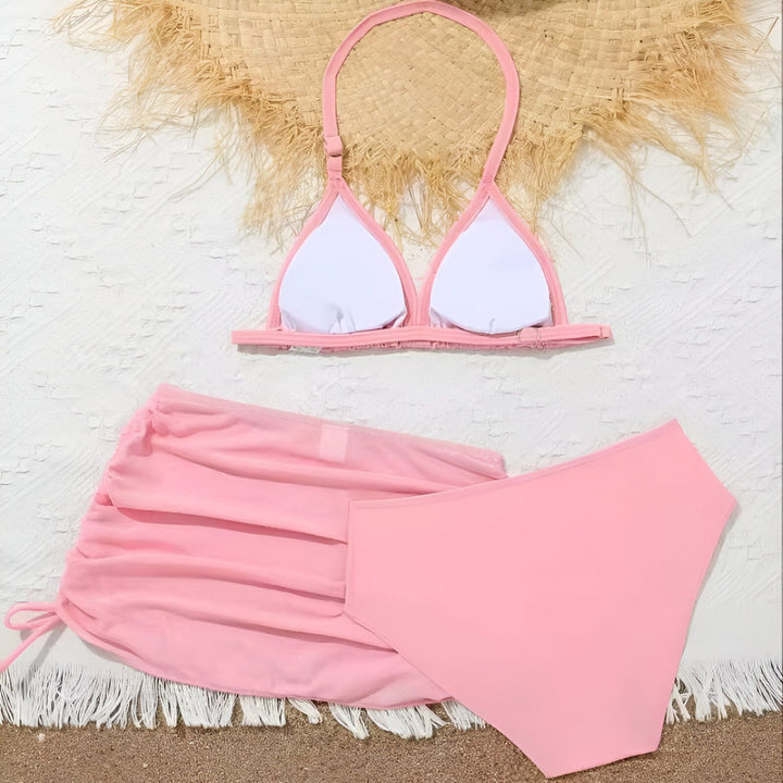 Ensemble de bikini rose avec jupe assortie, coquillage, fraises et chapeau de paille pour une ambiance estivale et vacances à la plage.
