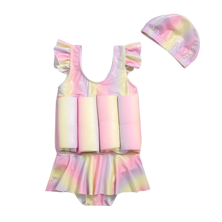 Maillot de bain flottant pour bébé, couleurs pastel arc-en-ciel, avec des flotteurs intégrés et une jupe à froufrous. Une macaron rose est à côté.