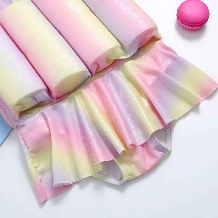 Maillot de bain flottant pour enfants, motifs multicolores pastel, avec des flotteurs intégrés et un bonnet assorti. Idéal pour apprendre à nager en toute sécurité et avec style.
