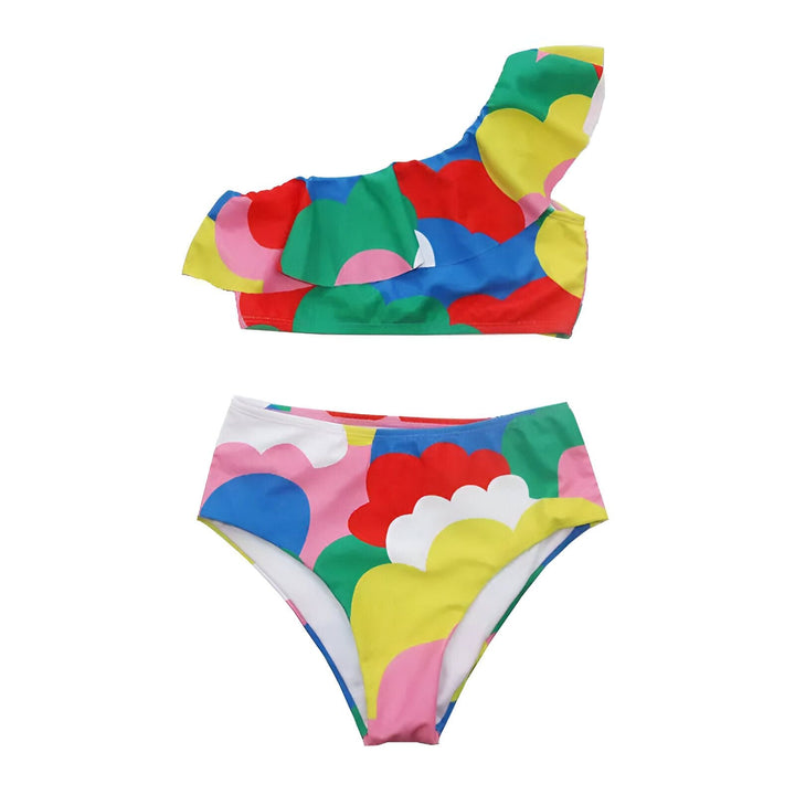 Détail d'un bas de maillot de bain coloré avec un motif de nuages/formes abstraites en rouge, rose, bleu, vert et jaune sur fond blanc. Le tissu est lisse et extensible.