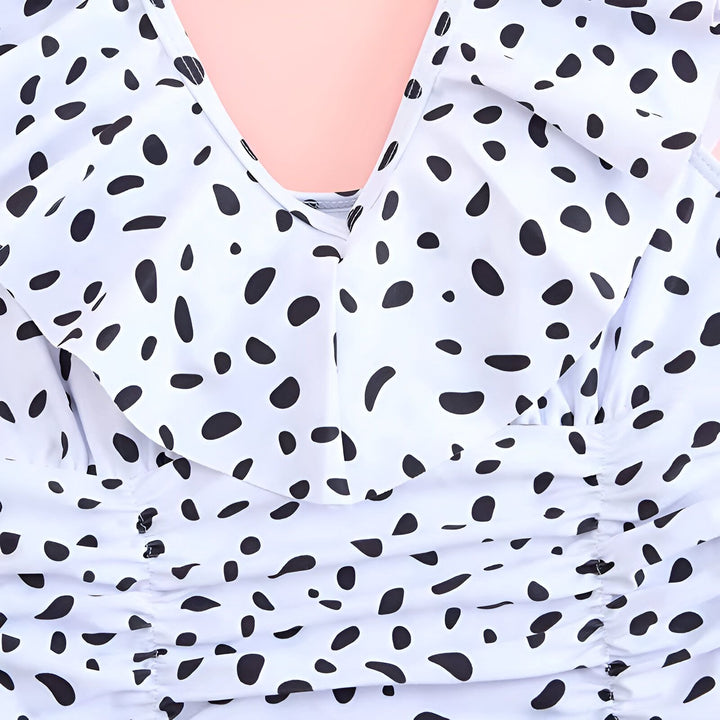 Gros plan d'un maillot de bain une pièce blanc à pois noirs avec un décolleté plongeant et des volants. Motif audacieux et détails froncés. Idéal pour la plage ou la piscine. Mode estivale.