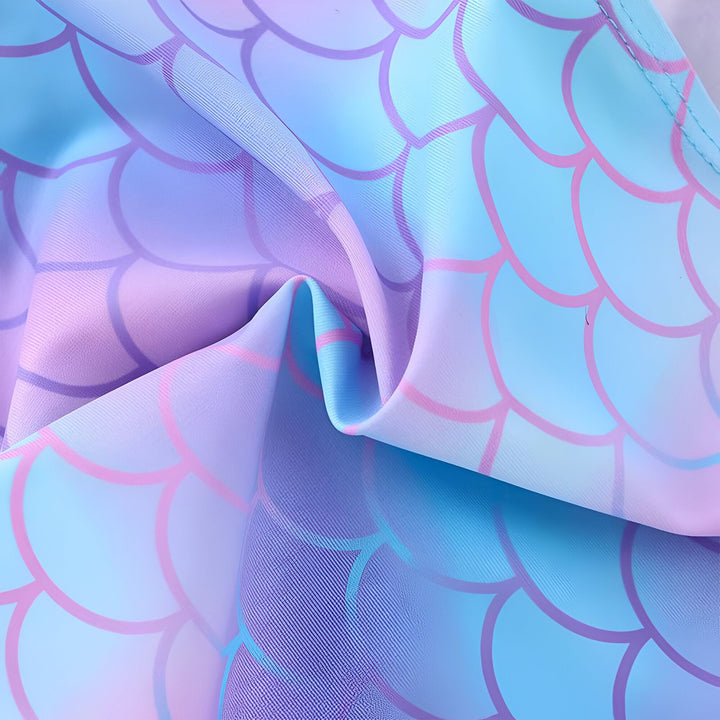 Texture tissu à motifs d'écailles de sirène dans les tons bleu, violet et rose. Détails plissés ajoutant du relief. Idéal pour vêtements ou décoration sur le thème marin.