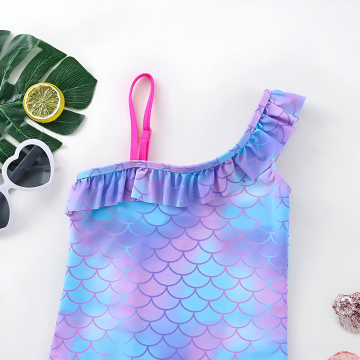 Maillot de bain une pièce pour fille avec motif écailles de poisson et Elsa de La Reine des Neiges. Volants violets et roses. Lunettes de soleil en forme de cœur et coquillages à côté. Idéal pour l'été et la plage.