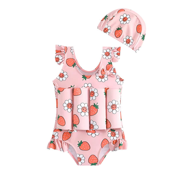Maillot de bain flottant pour enfant avec motif fraises et fleurs, et bonnet assorti. Des coquillages et une plante verte complètent l'ensemble estival.