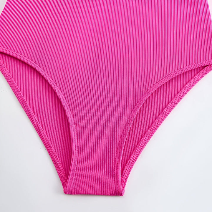 Gros plan d'un slip taille haute rose vif, en tissu côtelé avec des coutures fines, sur fond blanc.