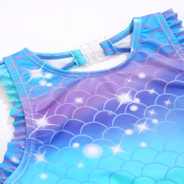 Gros plan d'un maillot de bain pour fille avec un motif d'écailles de sirène en bleu, violet et blanc. Détails de volants et fermeture transparente. Mode enfantine pour l'été.
