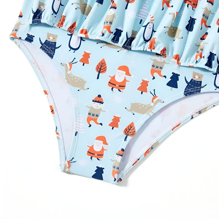 Vue rapprochée d'une robe d'été pour enfant de couleur bleu clair avec des motifs d'animaux hivernaux comme des ours, des pingouins et des rennes avec des bonnets de Noël et des motifs d'arbres.