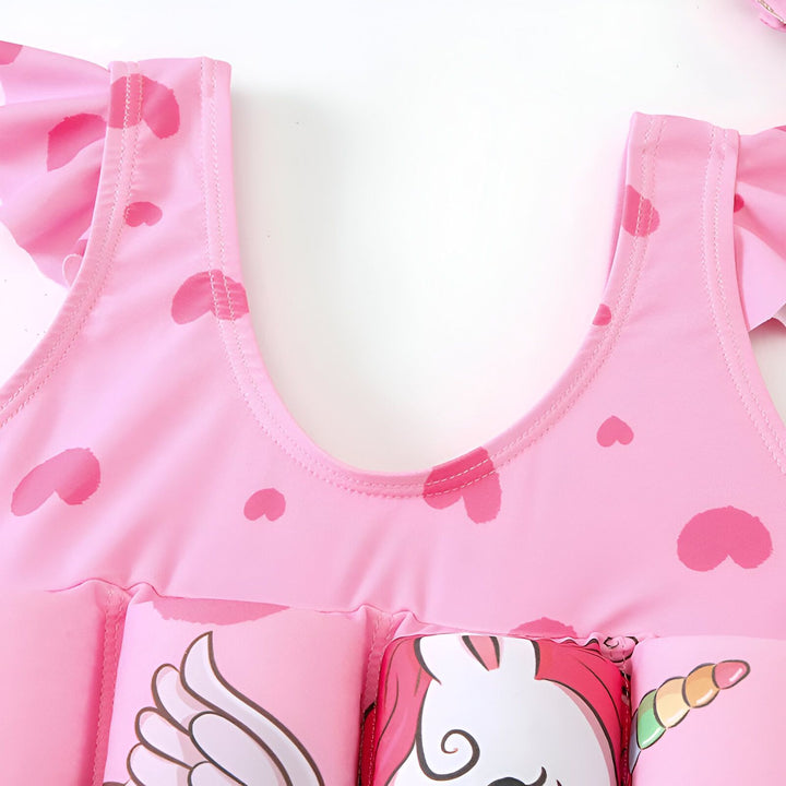 Gros plan sur un coussin rose pour enfant avec un motif de personnage de dessin animé et un rembourrage en mousse blanche, reposant sur un tissu rose à motif de cœurs. Détail d'accessoire pour enfant.