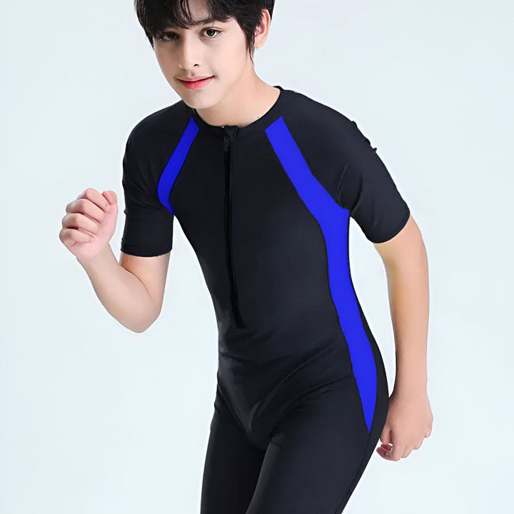 Jeune personne souriante en maillot de bain noir et bleu, avec bouée de sauvetage rouge et blanche sur l'épaule, sur fond blanc. Idéal pour la natation, la sécurité aquatique et les sports nautiques.