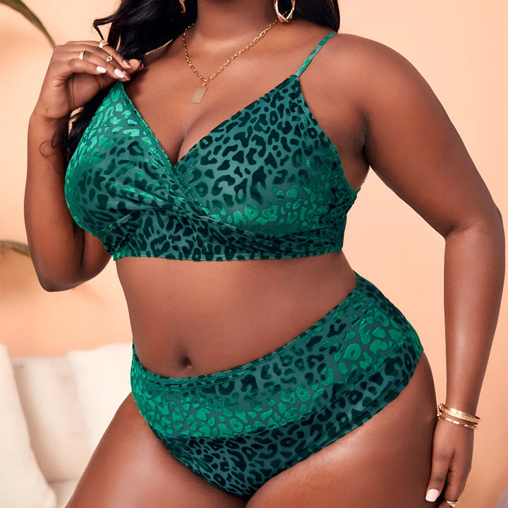 Une femme noire portant un ensemble de lingerie vert à motif léopard. Elle porte des bijoux dorés, y compris une chaîne, des boucles d'oreilles et des bracelets. Elle se tient à côté d'une forme mannequin blanc.