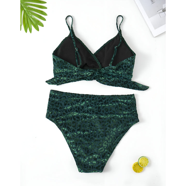 Femme vue de dos portant un bikini vert à motif léopard, avec des bretelles fines et un nœud dans le dos. Le bas est taille haute. Elle porte des bijoux dorés, des boucles d'oreilles et un bracelet.