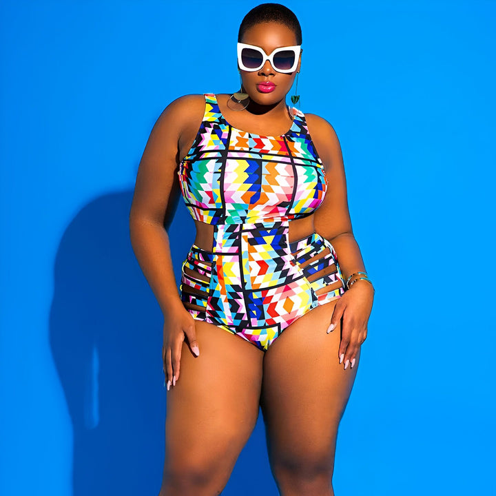 Femme noire souriante portant un maillot de bain une pièce coloré avec des motifs géométriques sur fond bleu. Elle a des cheveux bouclés, des boucles d'oreilles pendantes et un bracelet.