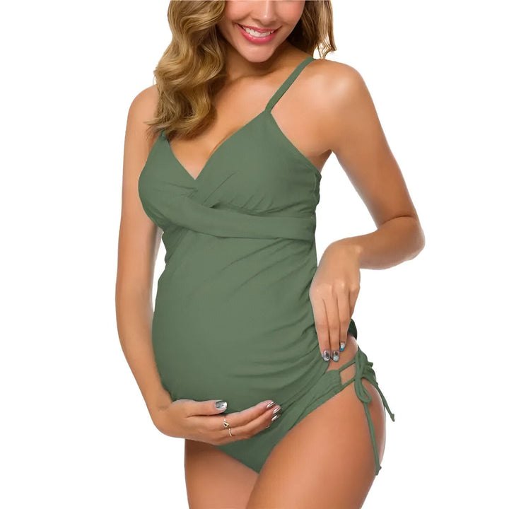 Femme enceinte souriant portant un maillot de bain une pièce à imprimé floral coloré.