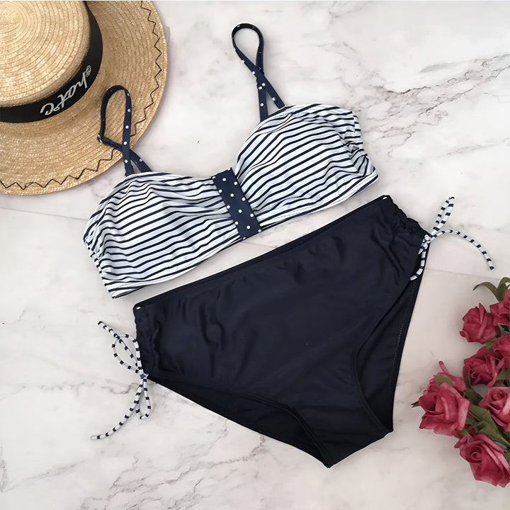 Femme enceinte en maillot de bain deux pièces rayé bleu et blanc. Ensemble de maternité pour la plage ou la piscine. Vêtement de grossesse confortable et tendance.