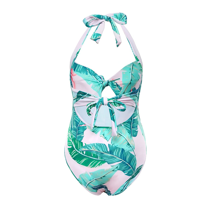 Maillot de bain une pièce blanc et vert à motif de feuilles tropicales, dos nu, noué à la nuque et au centre. Idéal pour la plage et la piscine.