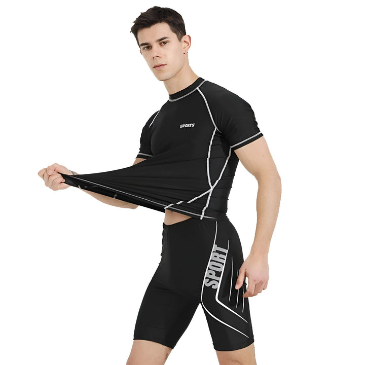Homme en maillot de bain noir moulant, révélant ses abdominaux. T-shirt manches courtes noir avec l'inscription "SPORTS" et short de bain assorti. Idéal pour la natation et les sports aquatiques.
