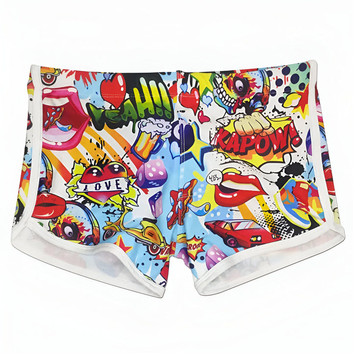 Homme torse nu portant un short de bain coloré avec motifs style bande dessinée, montrant ses tatouages sur les bras.